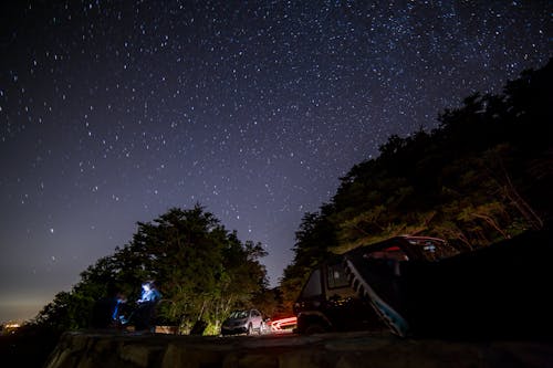 Free Vehicles Parked Near A Cliff Under A Starry Sky Stock Photo