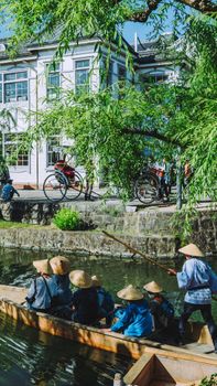 Experience a serene journey in a traditional canoe at Kurashiki Canal, Japan.