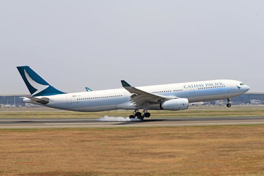 Cathay Pacific Airbus A330 landing on a runway with smoke trailing from wheels.