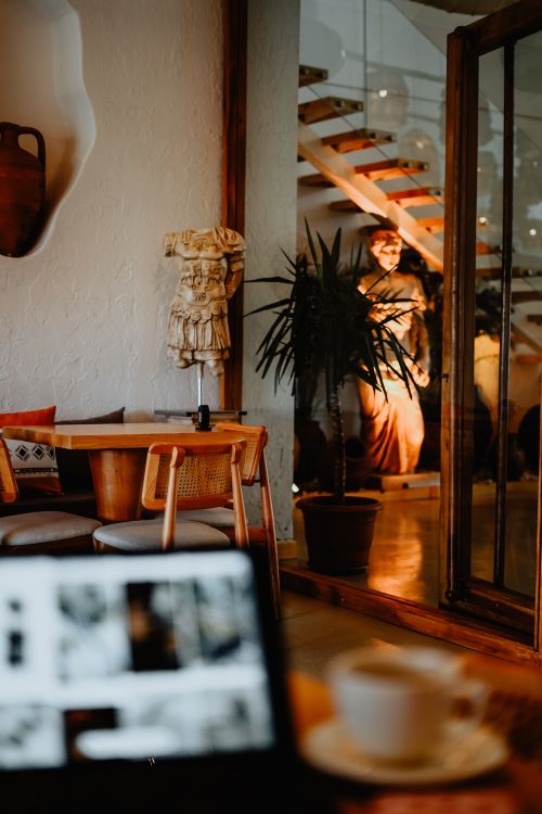Free Warm and inviting cafe interior featuring rustic decor, a staircase, and sculptures. Stock Photo