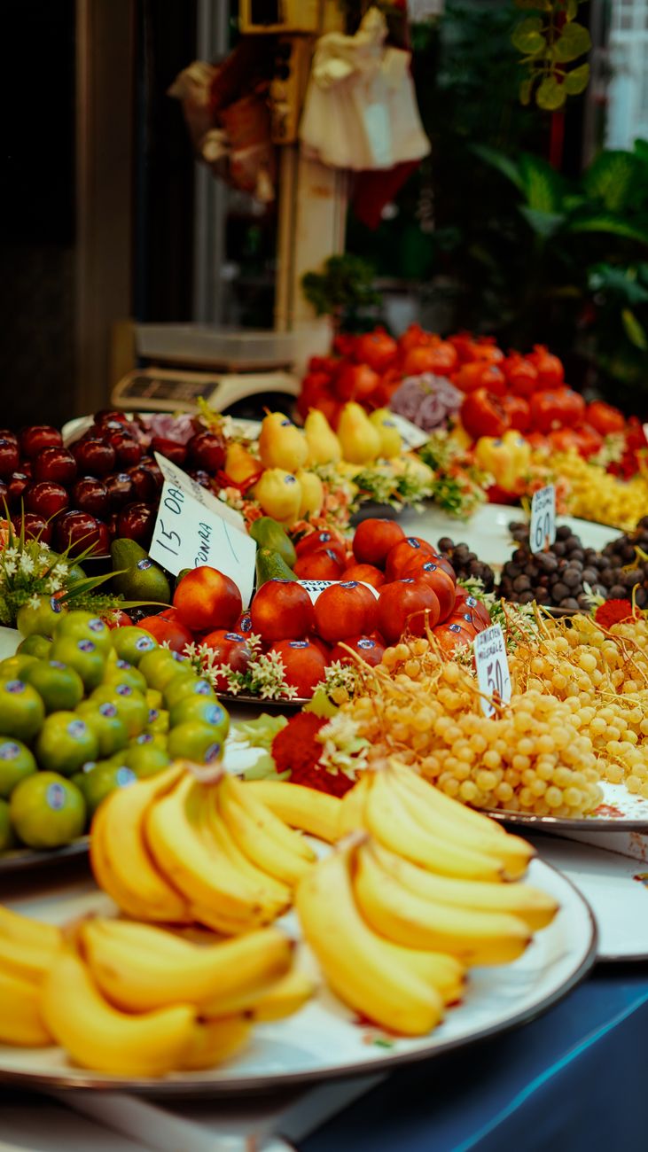 Vibrant display of fresh fruits including bananas, grapes, and apples in a street market setting.