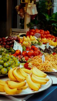 Vibrant display of fresh fruits including bananas, grapes, and apples in a street market setting.