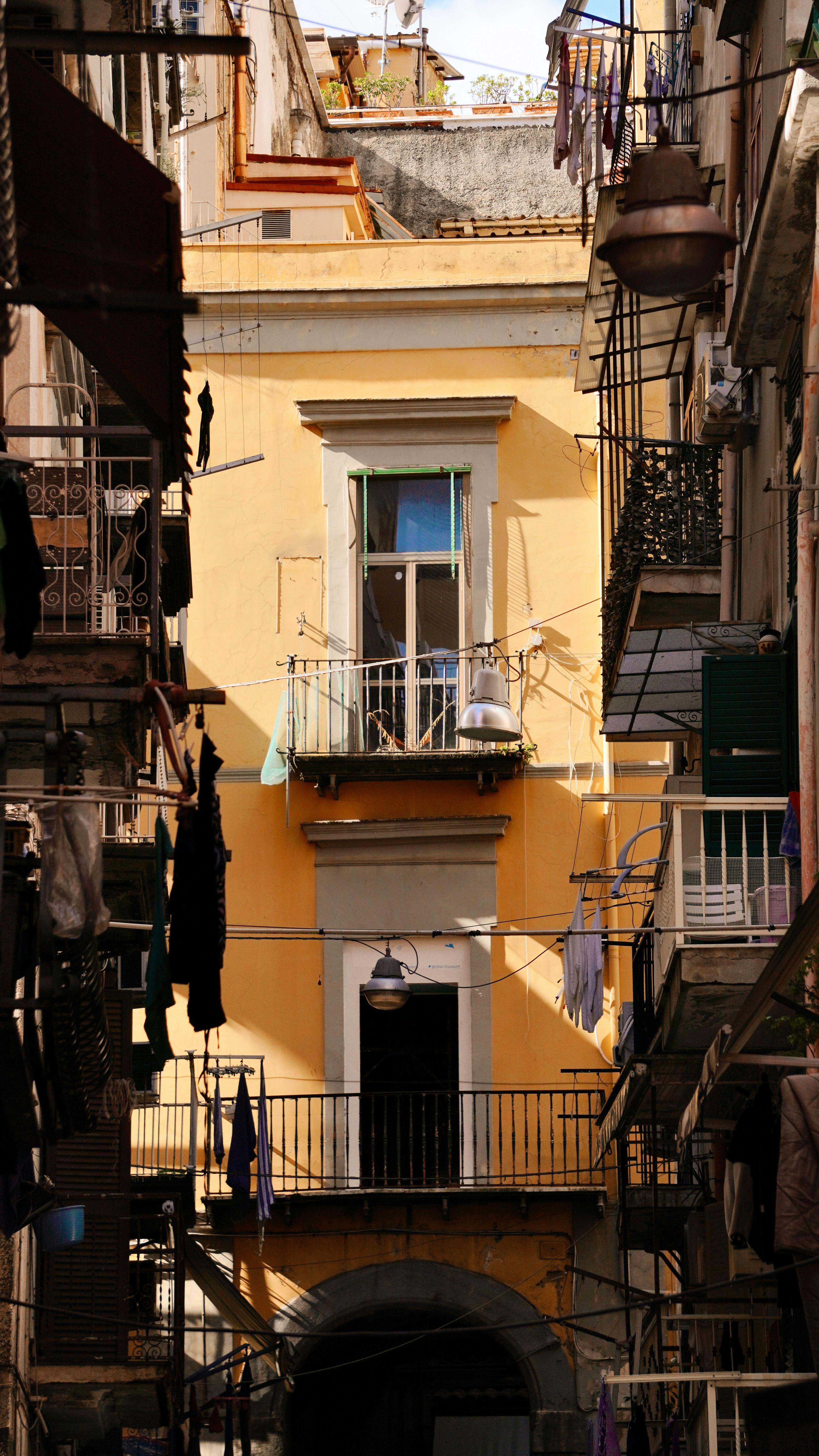 A narrow alley with laundry hanging between colorful historic buildings in Europe.