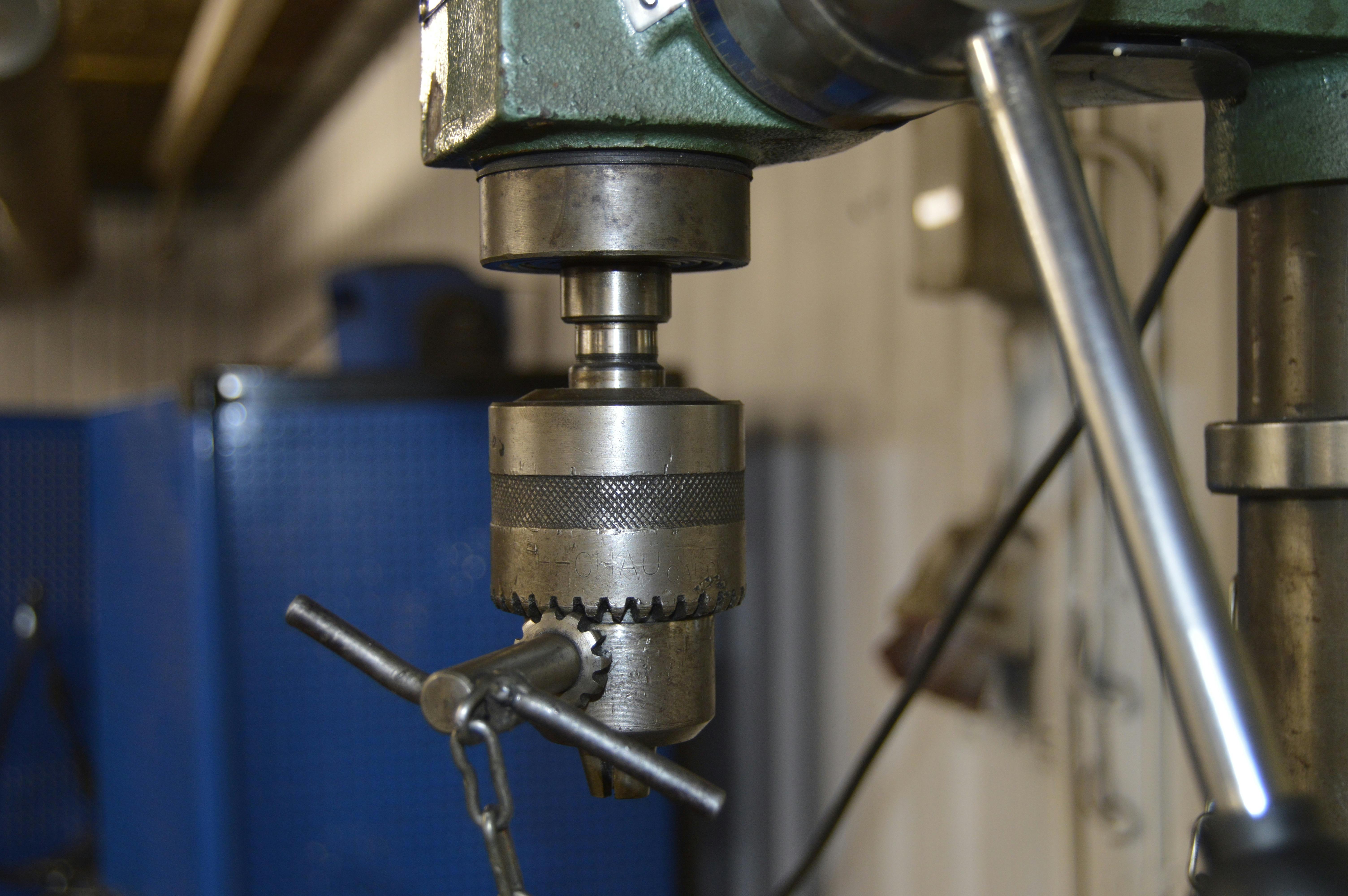 Close-up of a drill press in a Swedish workshop, showcasing industrial machinery.