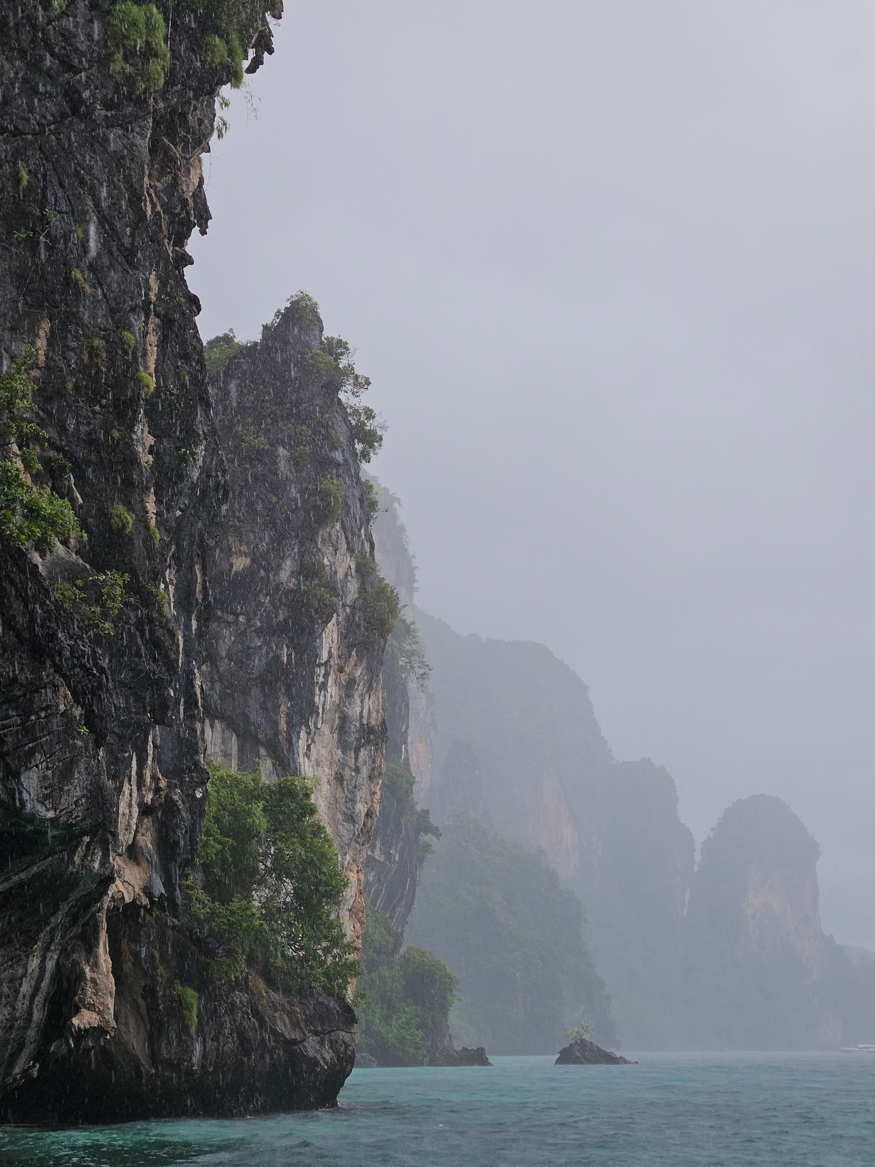 Rain over the Krabi River estuary with limestone karst hills in the background, Krabi, Thailand