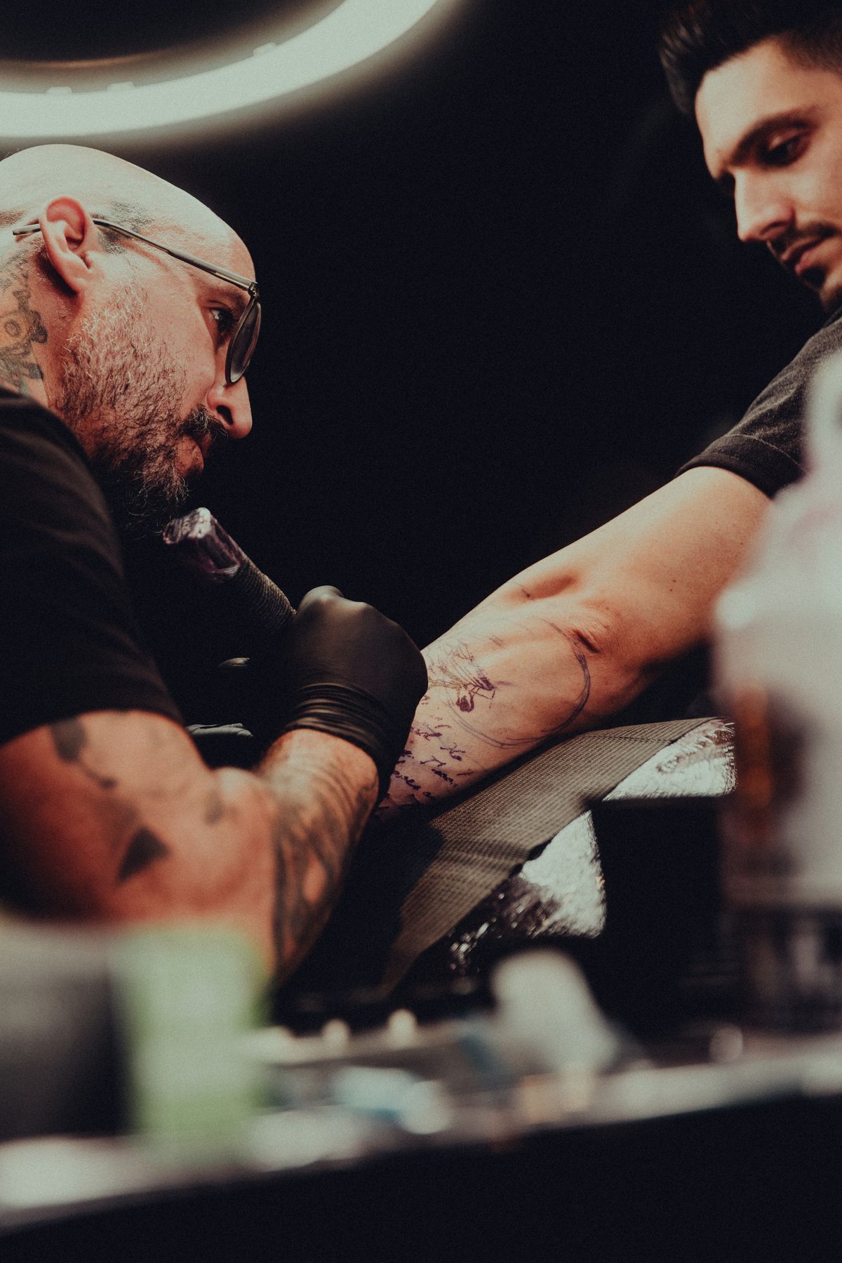 Tattoo artist working on a detailed arm tattoo