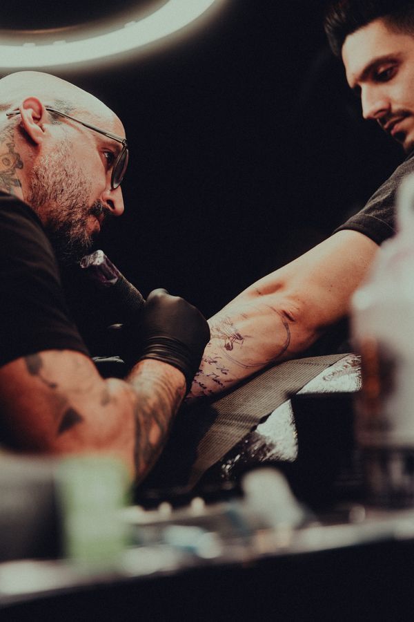 Artista tatuando, trabajo en brazo