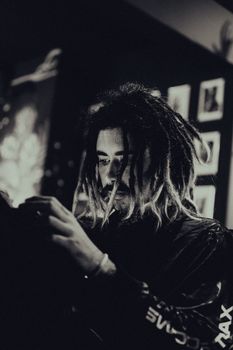 Moody portrait of a young man with dreadlocks in a tattoo shop.
