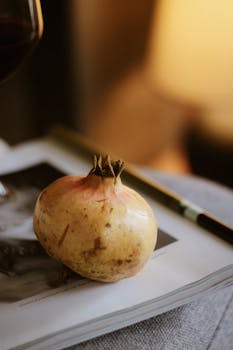 A still life of a pomegranate on a book, with warm lighting creating a cozy atmosphere.