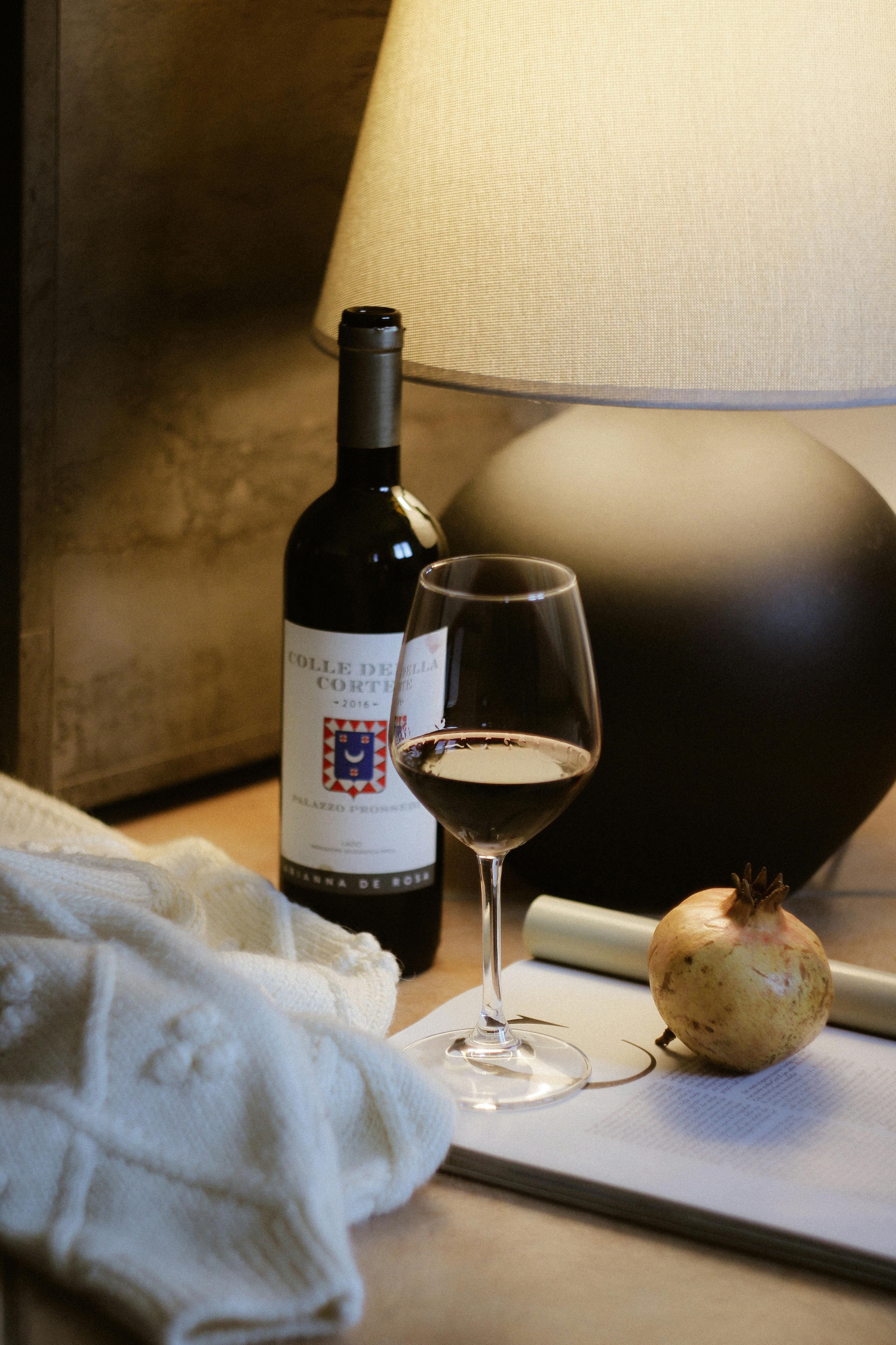 Warm and inviting evening setup with wine, glass, and lamp on a table.