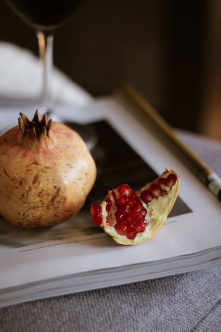 Artistic still life featuring a pomegranate on a magazine with warm tones.