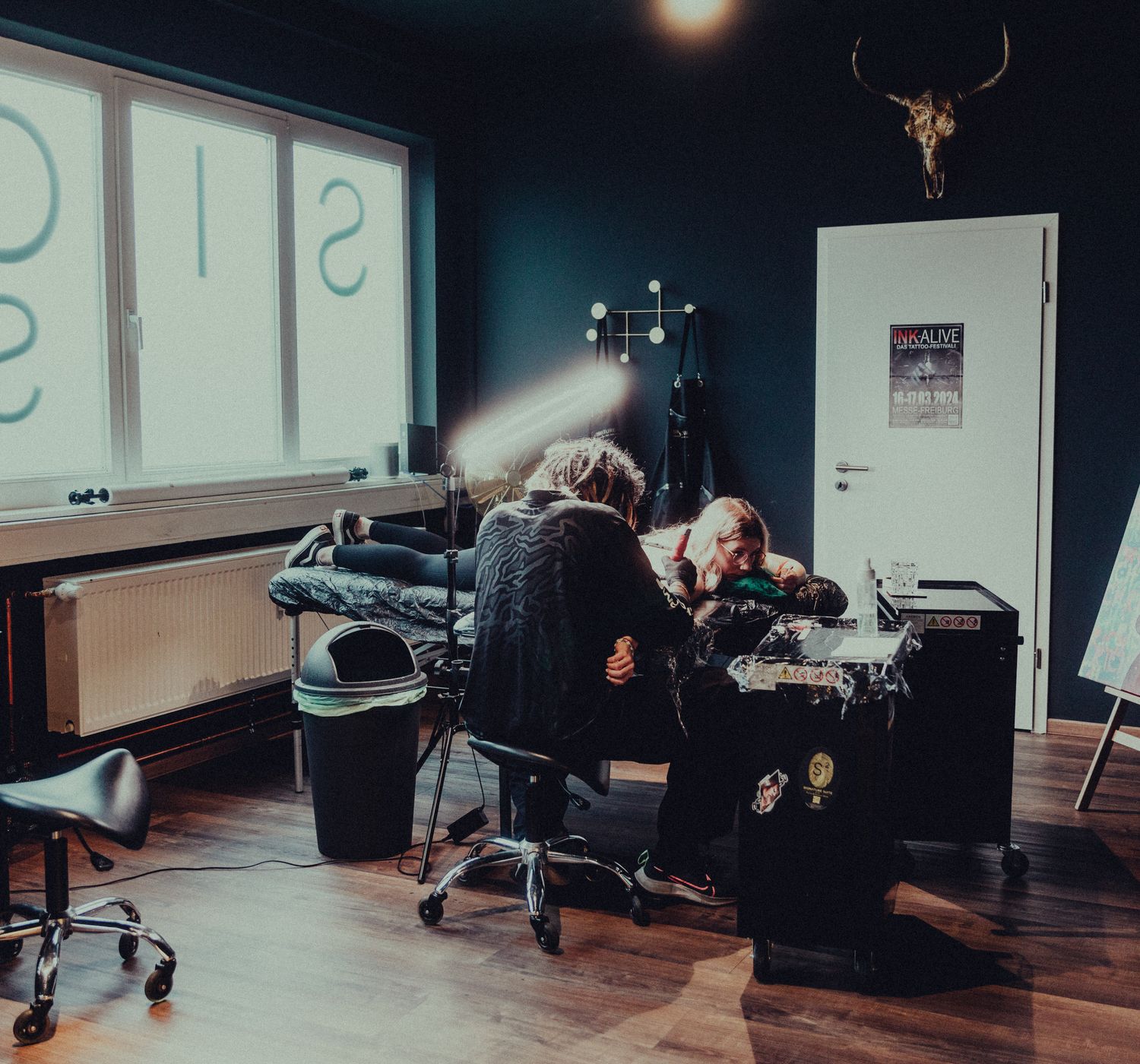 Tattoo artist working on a client in a modern studio, low ambient light.