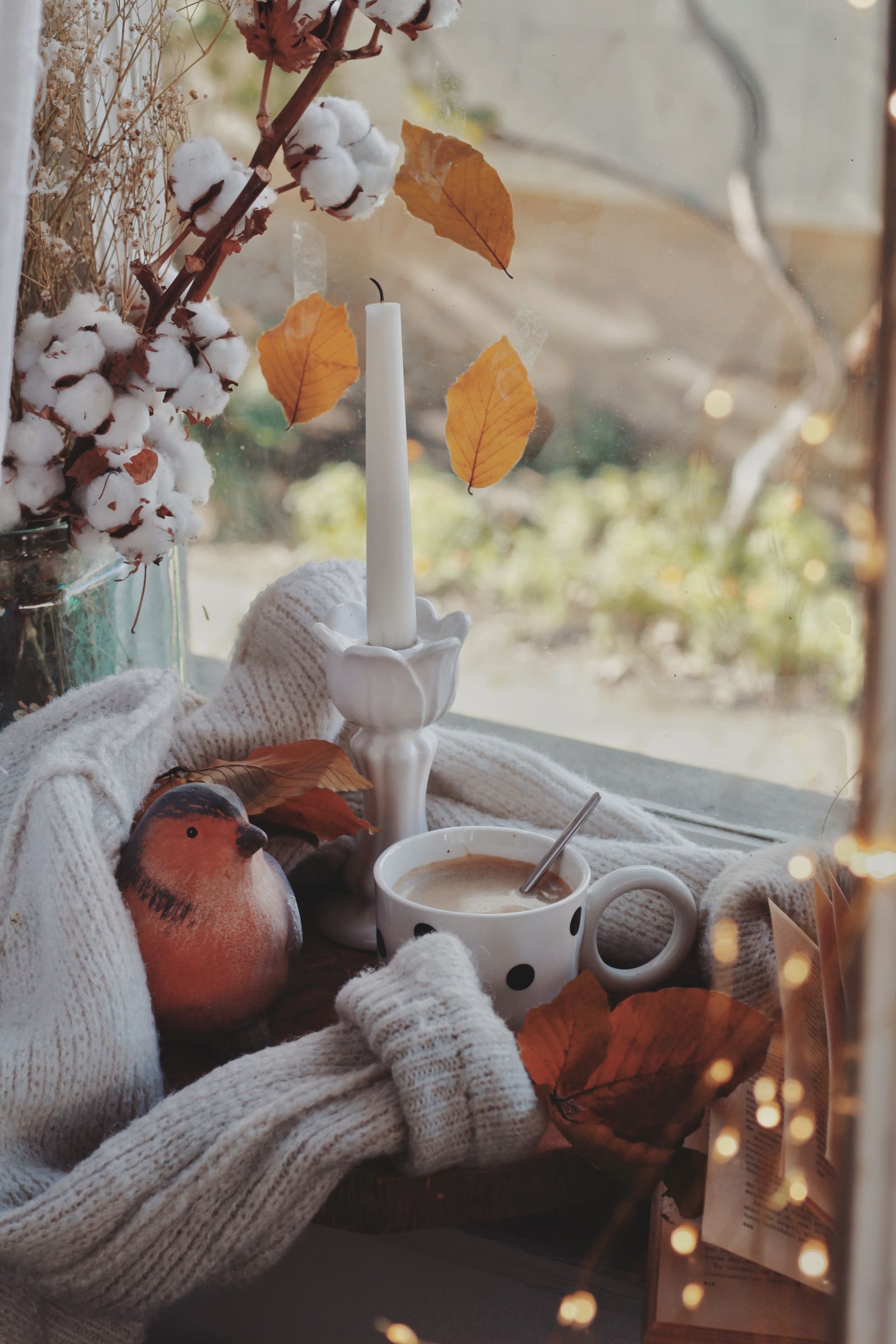 Herbstliche Szene am Fenster mit Kaffeetasse, Kerze und Laub