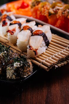 Assorted sushi rolls artfully arranged on a bamboo mat. Perfect for cuisine enthusiasts.