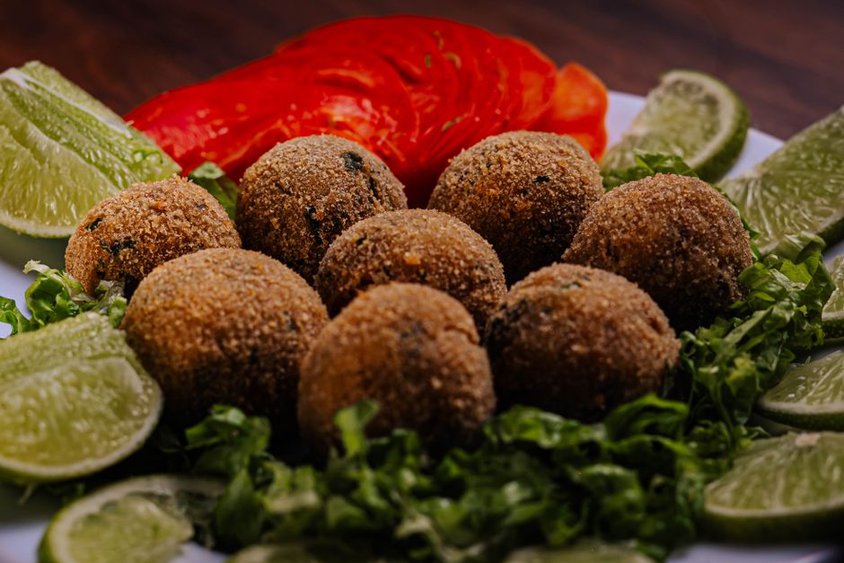 Krispiga falafelbollar på en bädd av strimlad sallad med limeklyftor och tomat