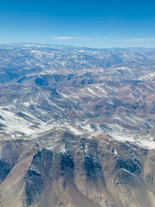 Free Breathtaking aerial view of snow-covered mountains under a clear blue sky. Stock Photo