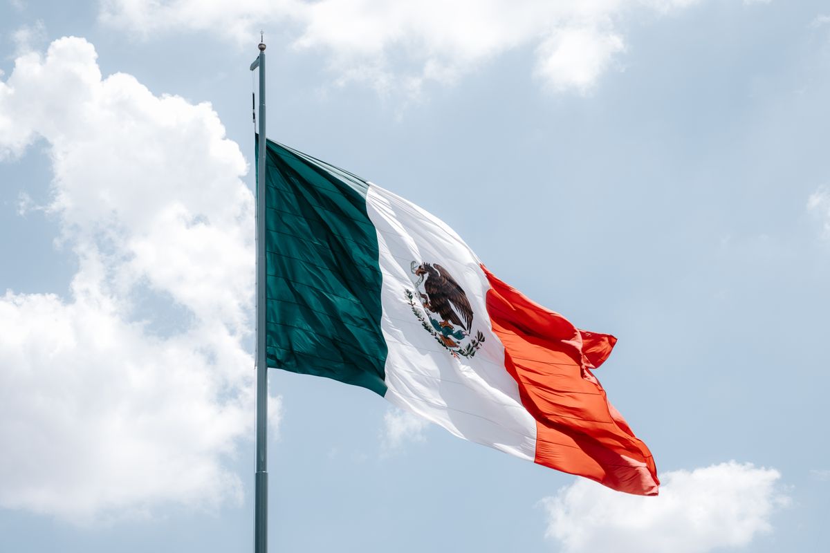 Vibrant Mexican flag waving against a bright blue sky in Mexico City.