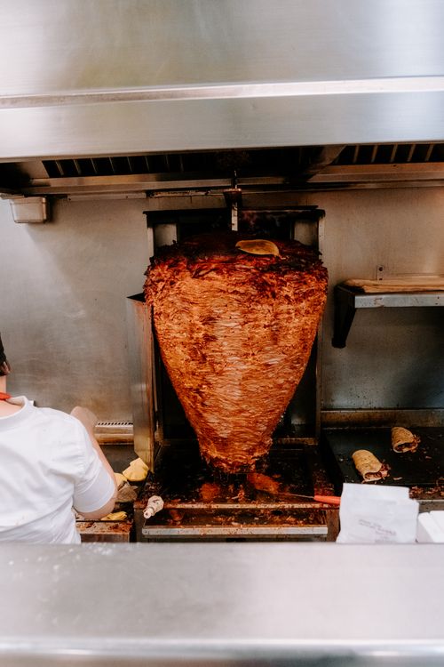Free A large spit roast of marinated Al Pastor meat in a traditional kitchen setting. Stock Photo