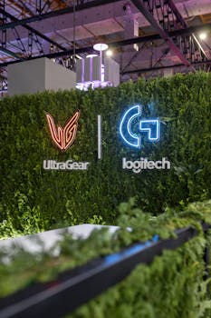 Lush greenery wall with illuminated UltraGear and Logitech logos at indoor exhibition.