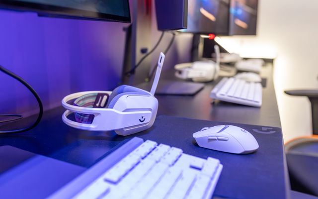 A white Logitech G733 headset on a desk beside a white keyboard and mouse