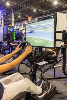 A person confidently navigates a virtual race simulator at an indoor gaming event.