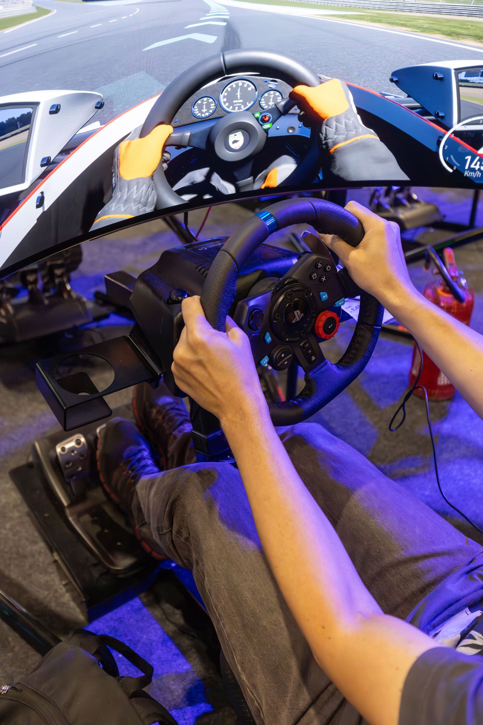 Player using an immersive racing simulator with steering wheel, pedals and display