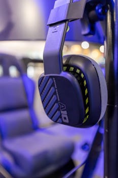 Close-up of gaming headphones in a modern tech setup with vibrant blue lighting.