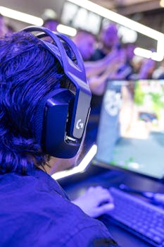 A gamer engrossed in an intense video game session wearing a high-tech headset with neon lighting effects.