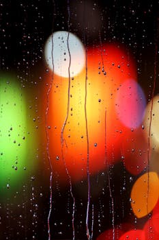 Raindrops on a window with vibrant bokeh lights creating an abstract pattern.