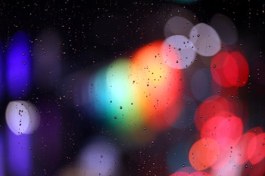 Vibrant bokeh lights through raindrop covered glass creating a colorful and artistic abstract scene.