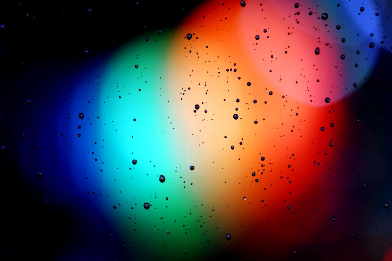 vivid abstract image with rainbow colors and water droplets on glass
