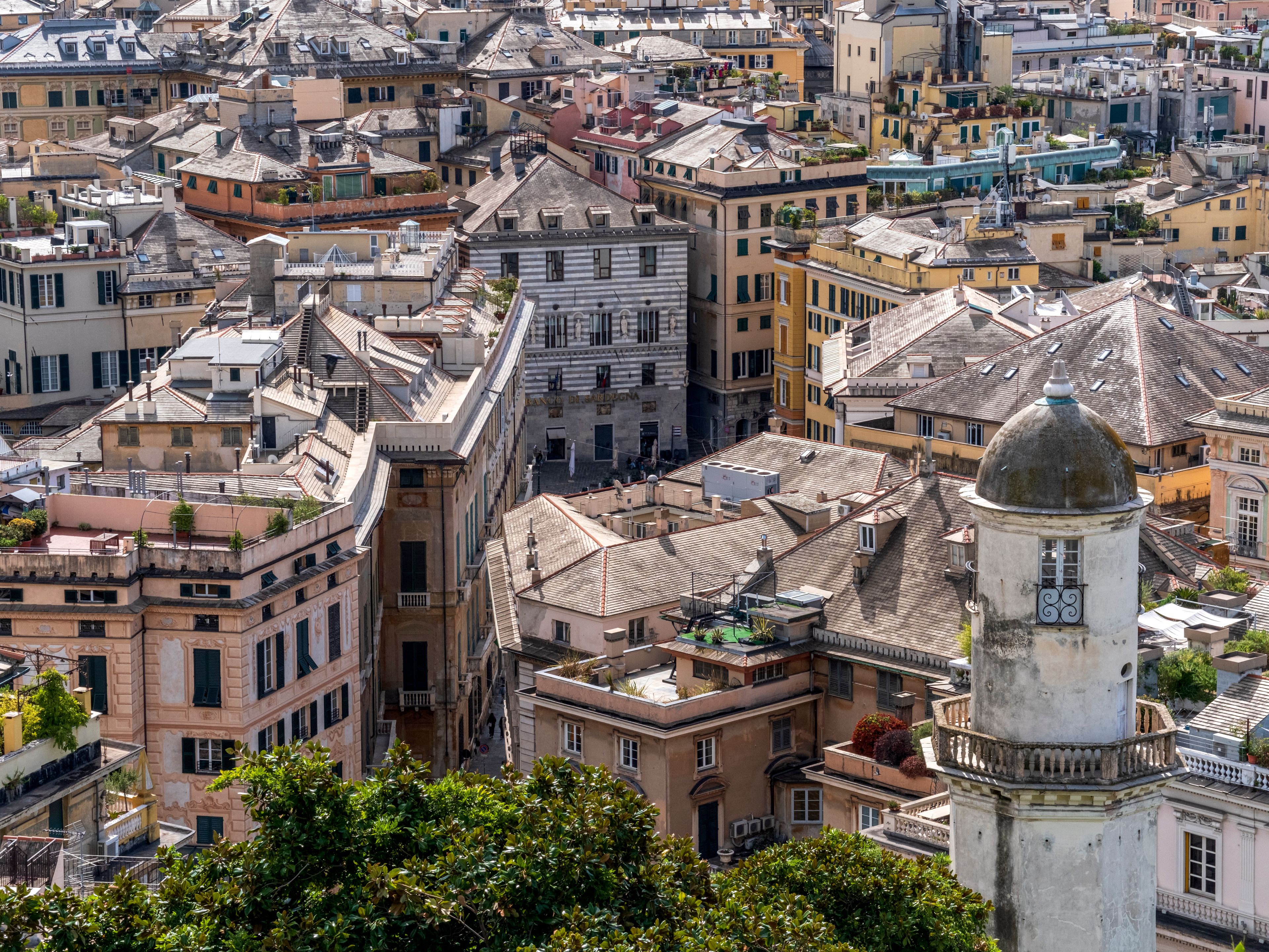 Vue en hauteur sur les toitures serrées et les cours intérieures d'un centre-ville ancien.