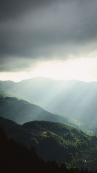 Dramatic sunlight beams through clouds over verdant Tokat mountains, Türkiye.