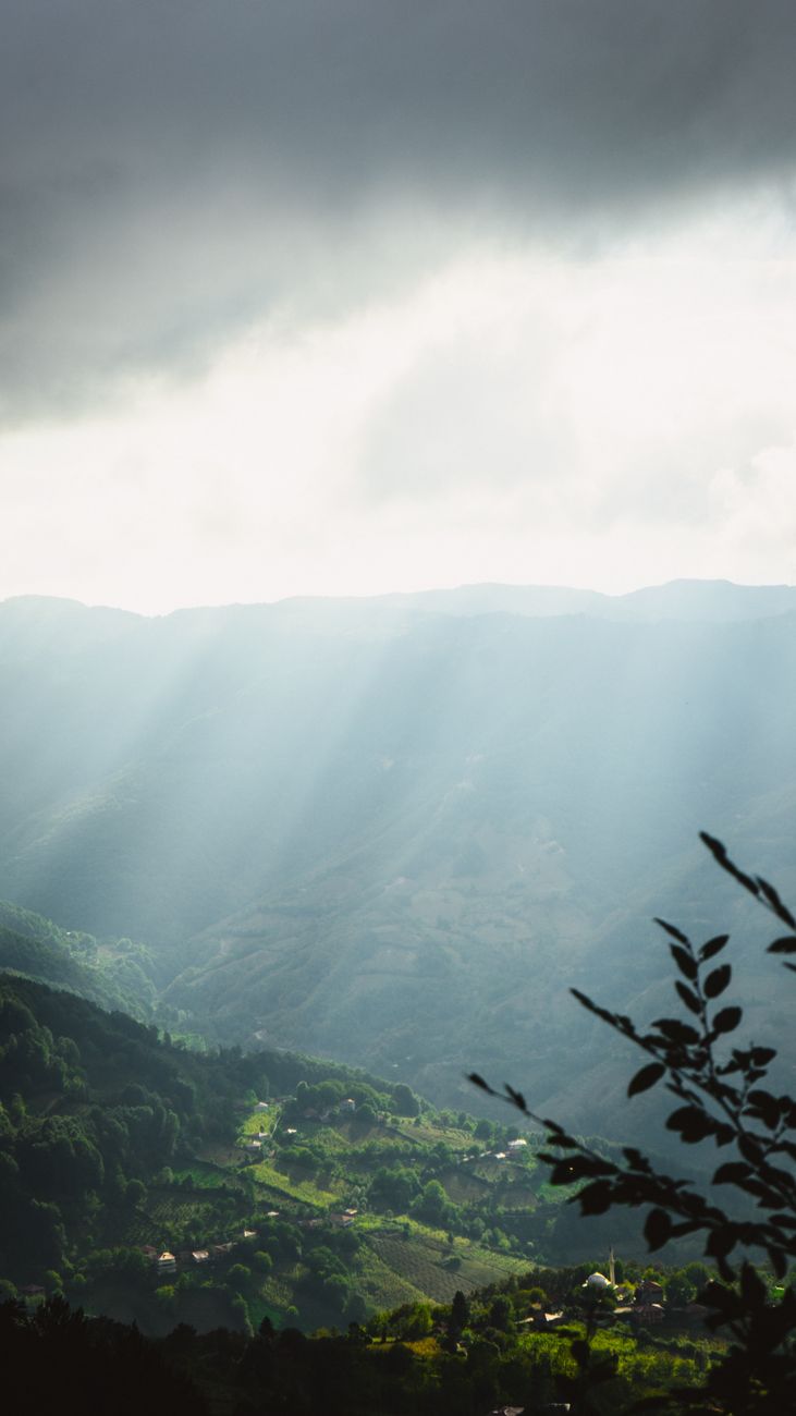 Serene mountain valley landscape with sun rays breaking through clouds in Erbaa, Türkiye.