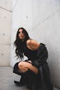 白天，在现代混凝土背景下，穿着黑色服装的时尚女性
