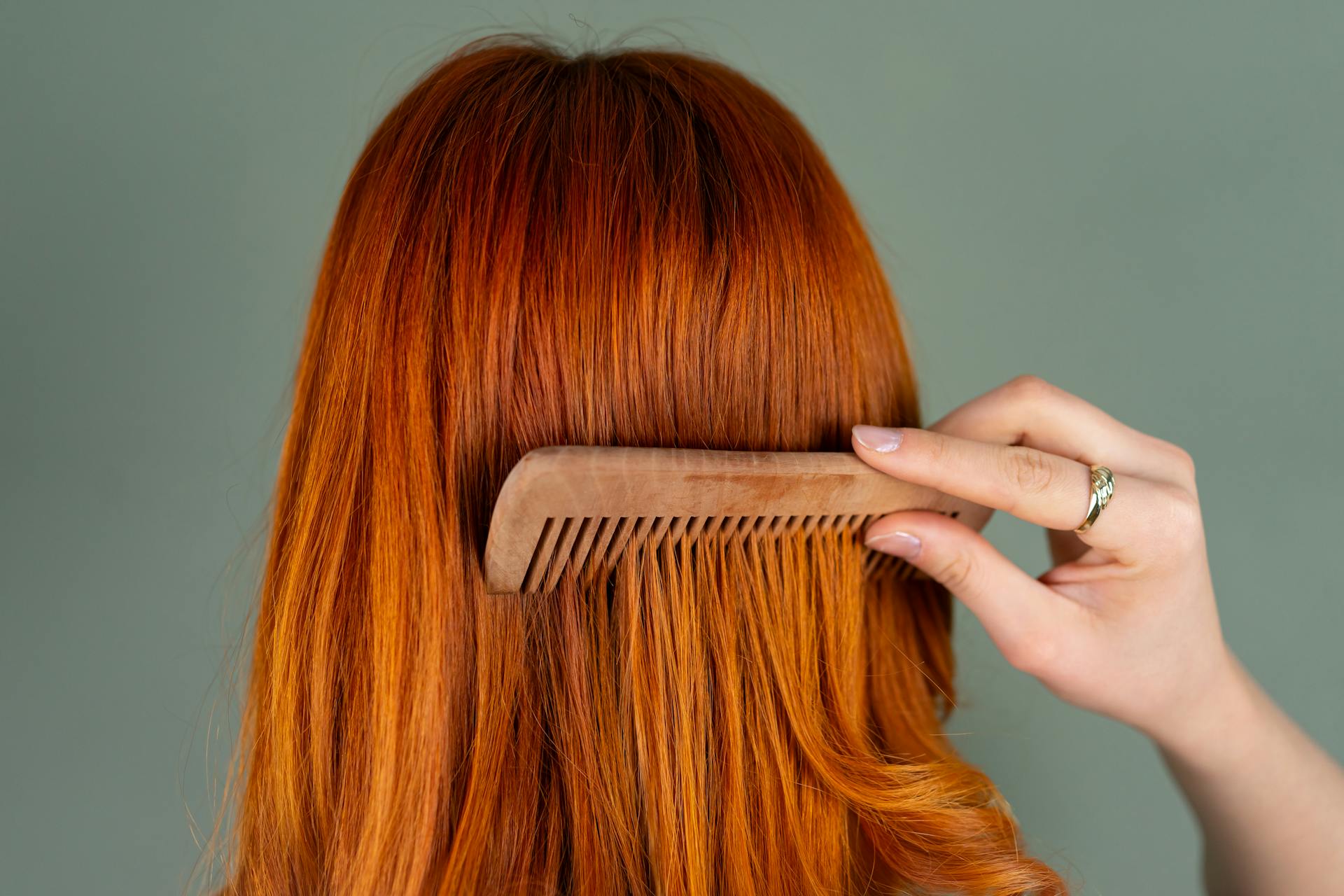 Vrouw kamt lang rood haar met een houten kam