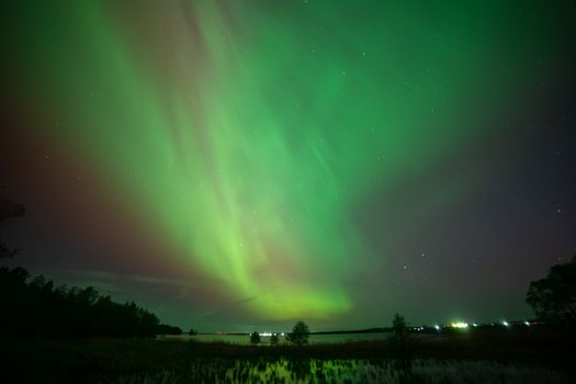 Capture of vibrant Northern Lights with starry sky over Belarusian landscape.