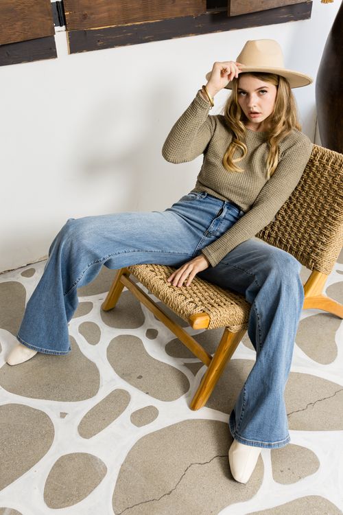 Free Young woman wearing a hat and casual outfit sitting stylishly indoors. Stock Photo