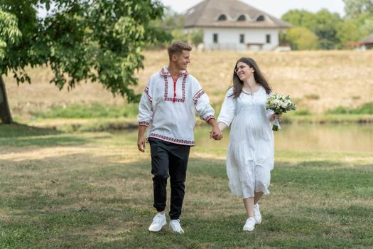A joyful couple in traditional attire walking hand in hand on a sunny day.