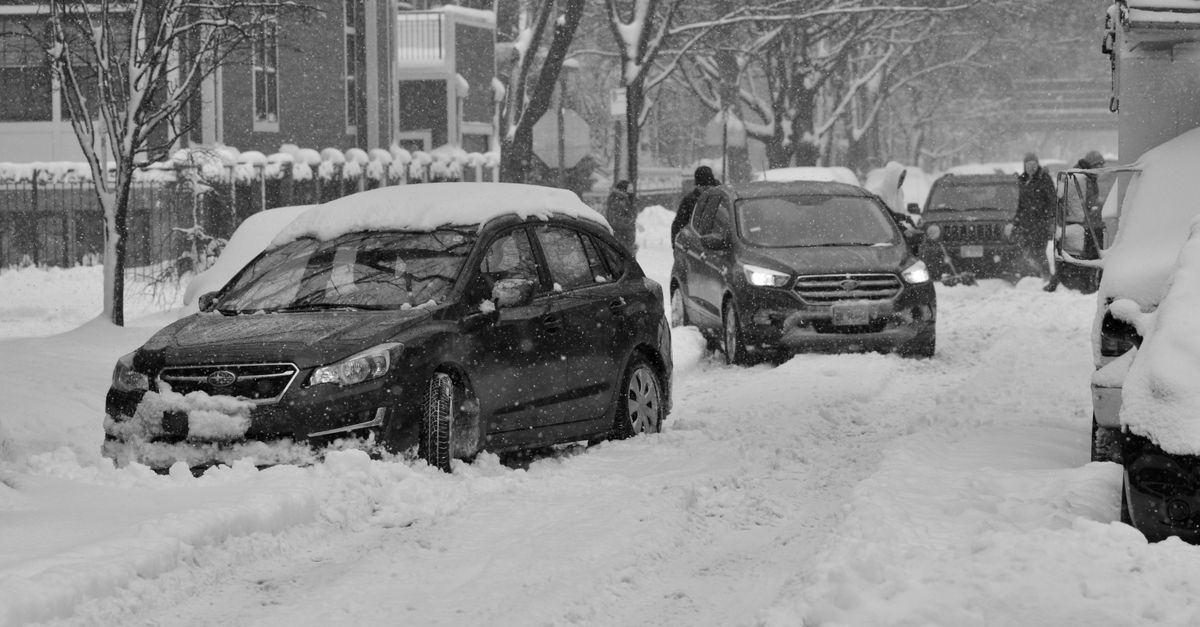 Cars stuck in snow on a snowy Chicago street during winter blizzard.