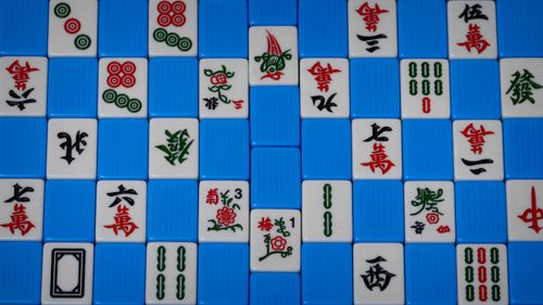 Free Detailed view of colorful Mahjong tiles arranged on a blue background, showcasing traditional symbols. Stock Photo