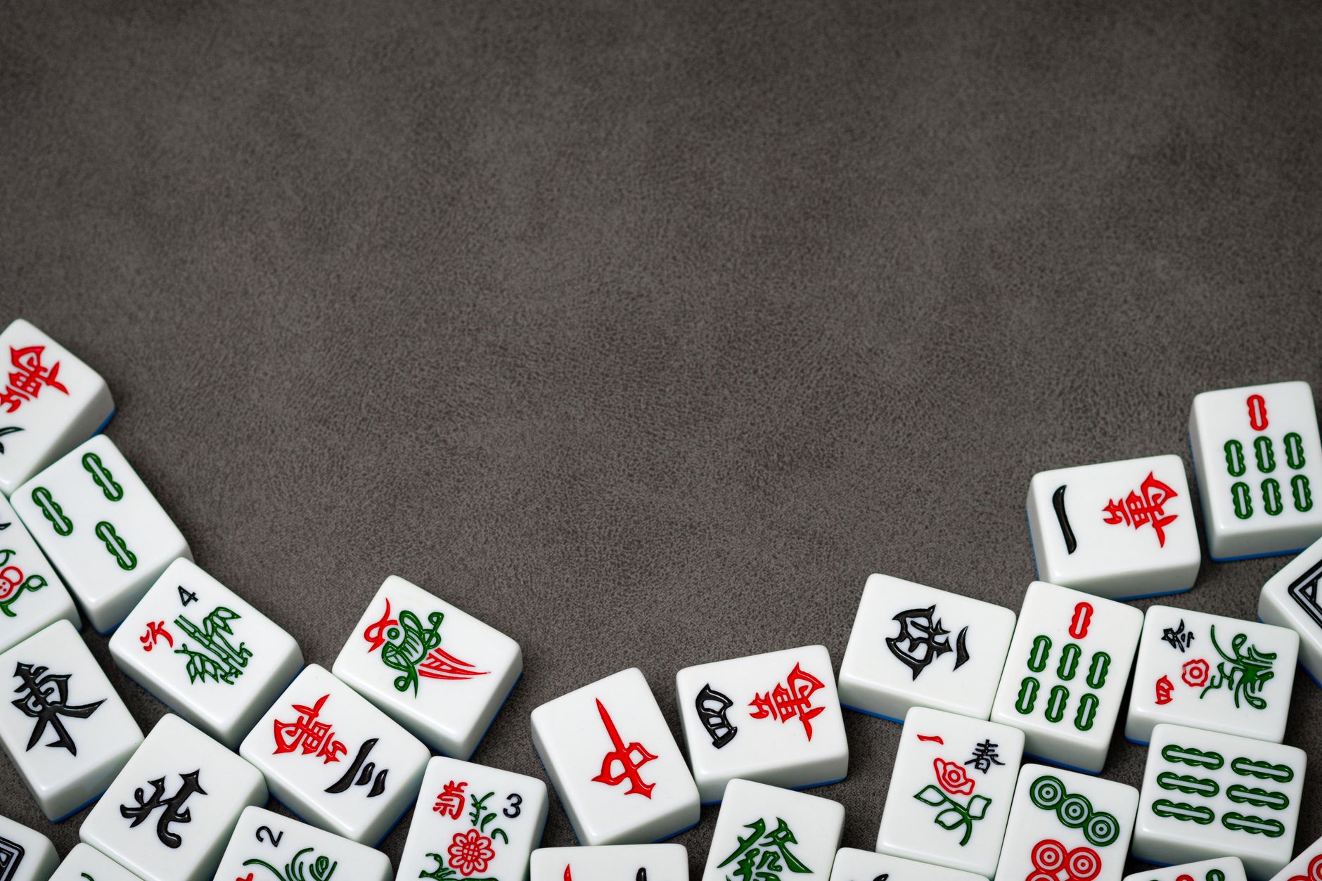 A collection of traditional Mahjong tiles arranged on a grey surface, perfect for board game concepts.
