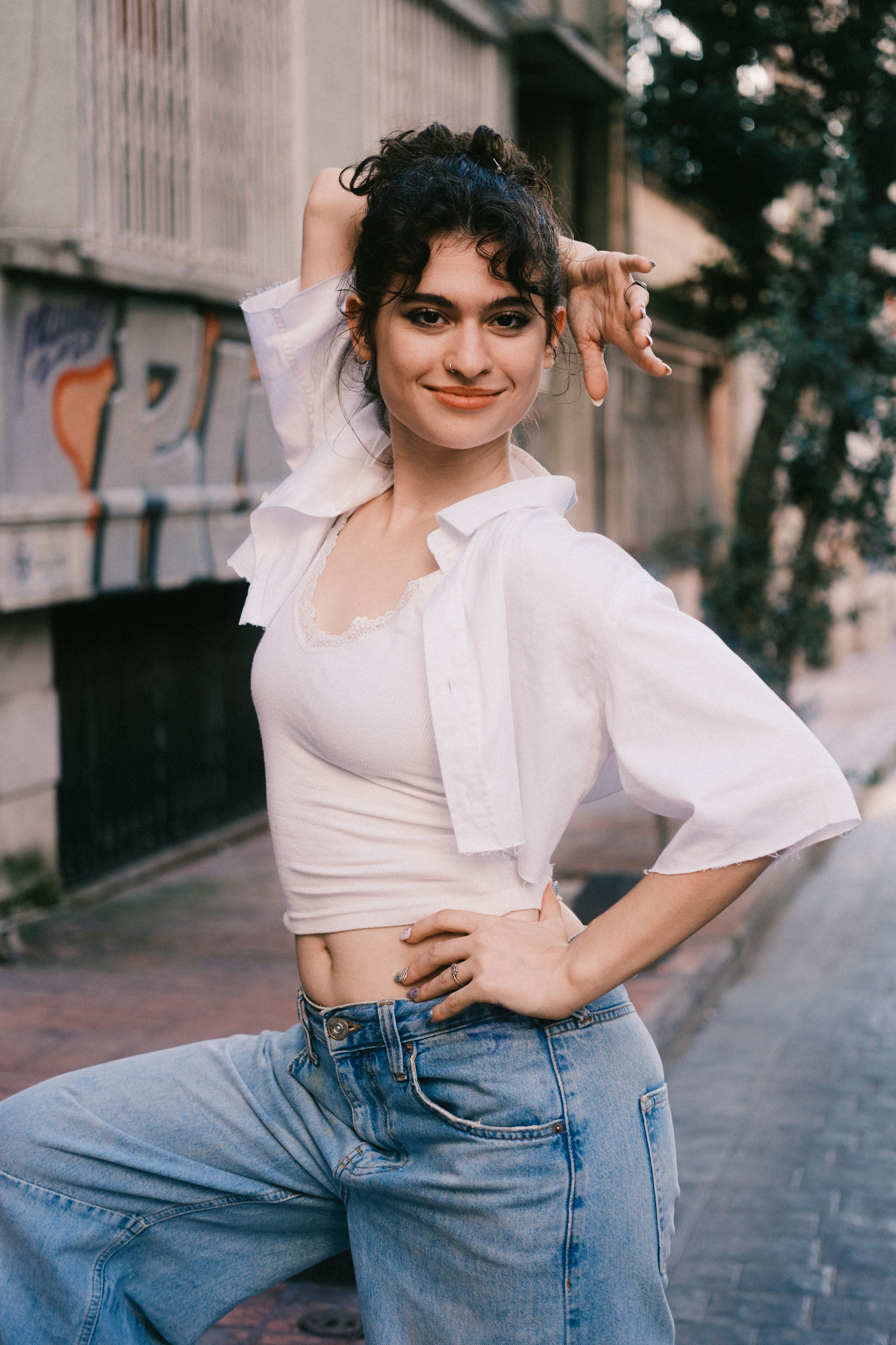 Young woman posing confidently in casual attire on an urban street.