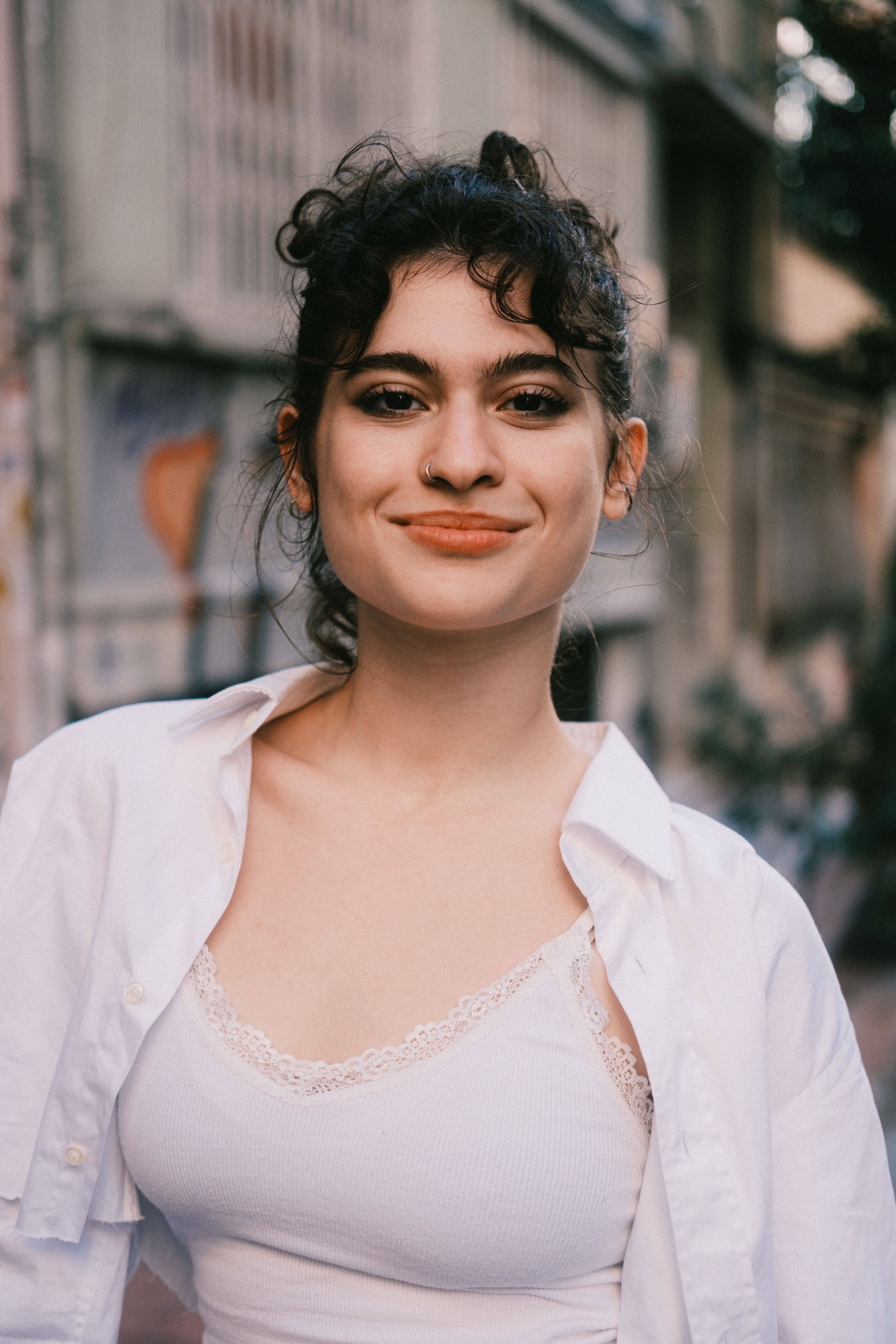 Portrait of a smiling woman in casual wear on an urban street, conveying confidence and warmth.