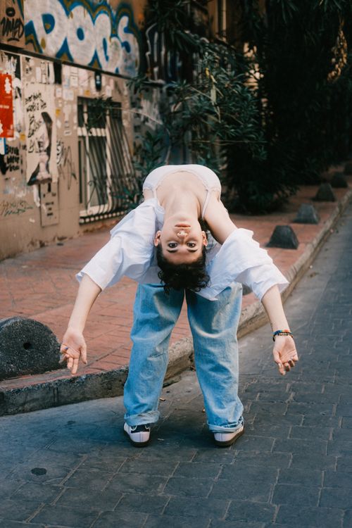Free Young adult bending backwards in a graffiti-lined urban alleyway. Stock Photo