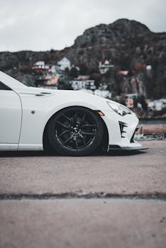 A stylish white sports car parked with a scenic mountainous backdrop, showcasing modern automotive design.
