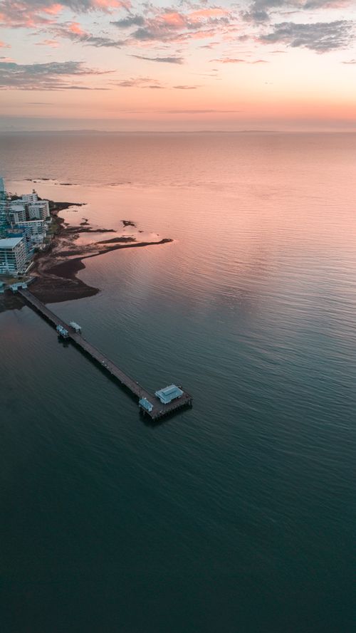 Free Stunning aerial shot of Woody Point Pier in Queensland during sunset creating a serene coastal scene. Stock Photo