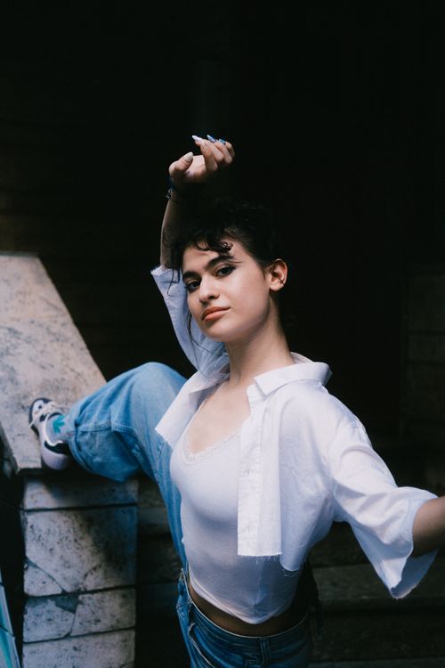 Free Confident young woman posing dynamically outdoors with urban vibes. Stock Photo