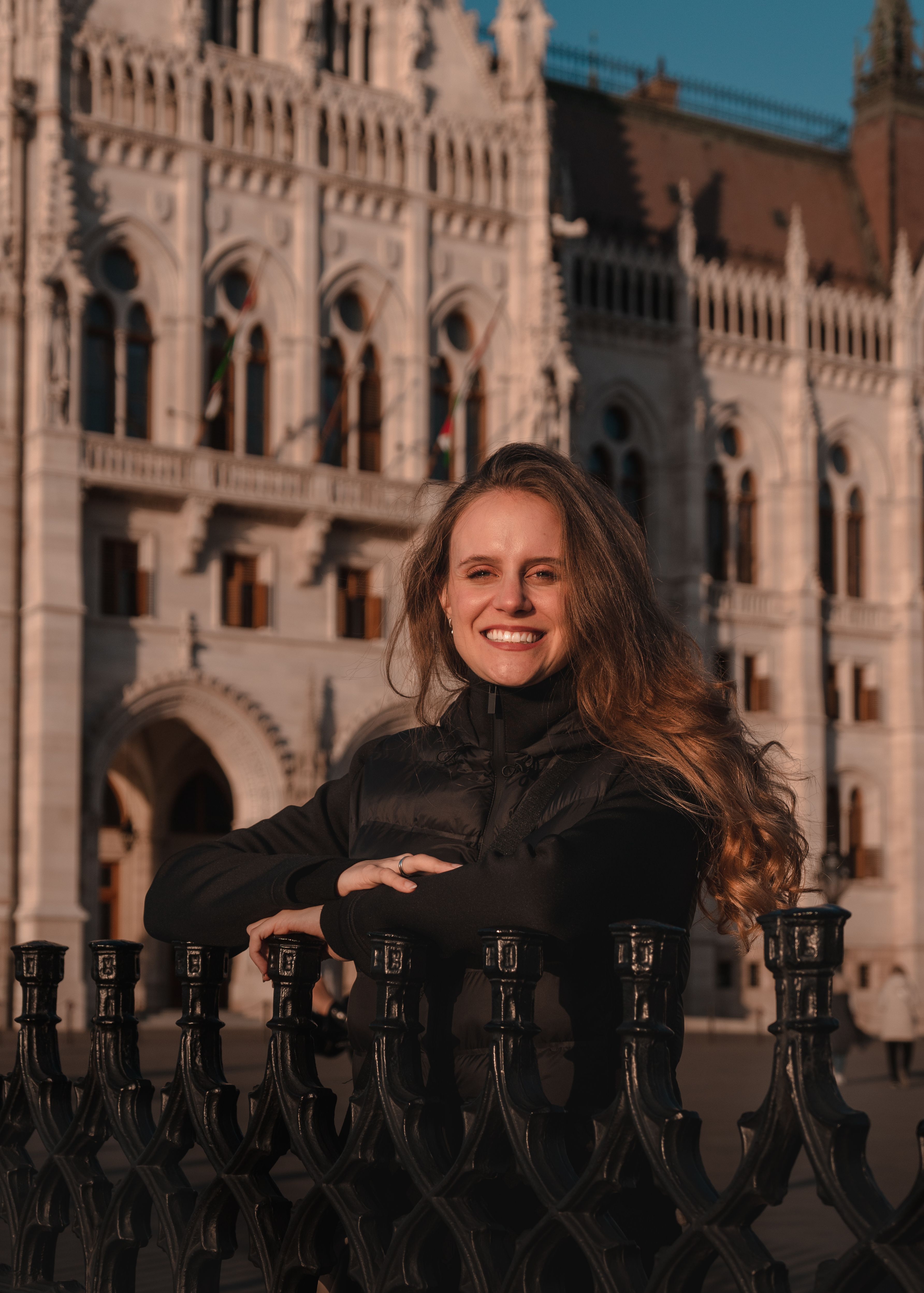 Woman smiling in front of the Hungarian Parliament Building in Budapest.