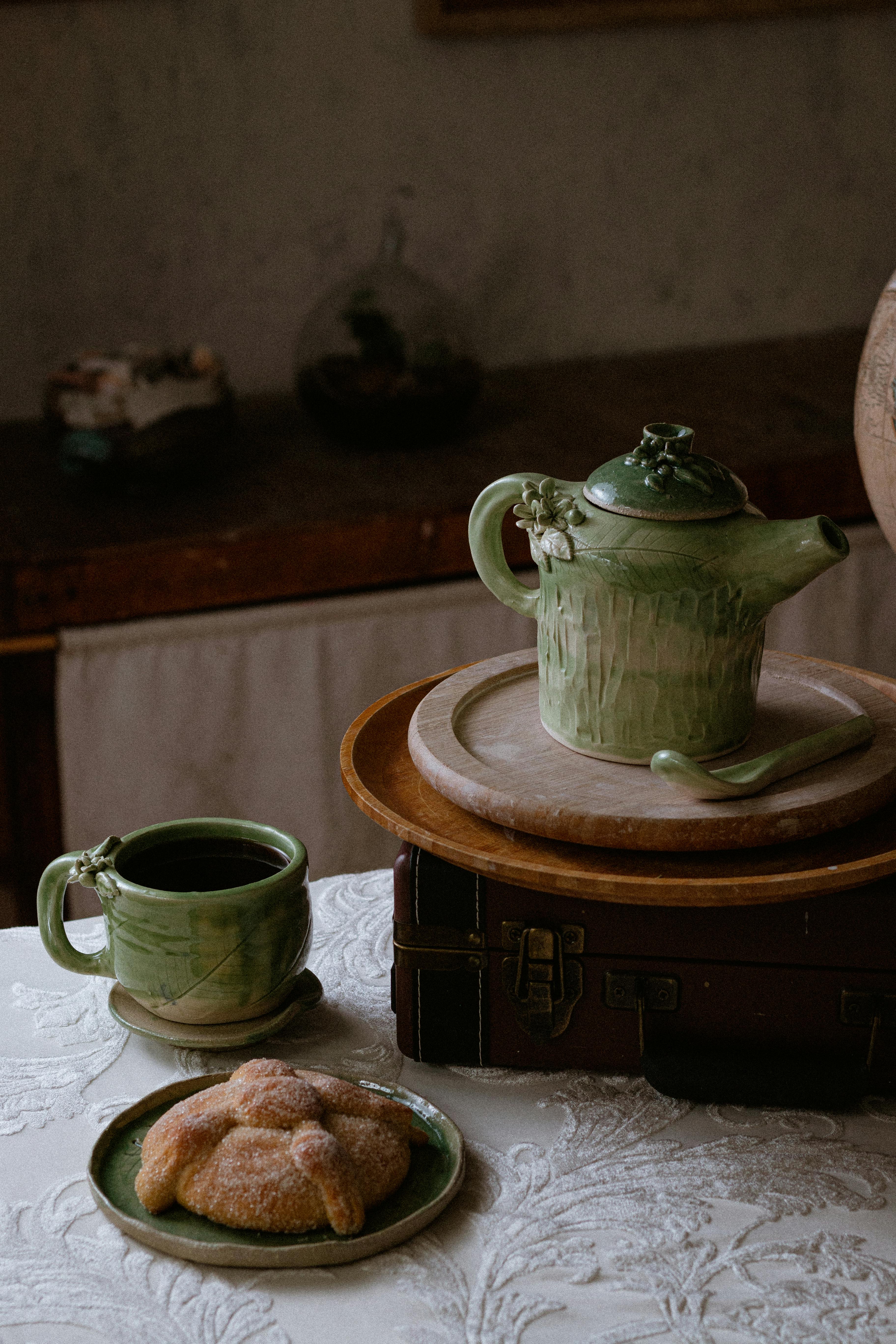 Handcrafted green pottery teapot and mug with Mexican sweet bread in rustic Chiapas setting.